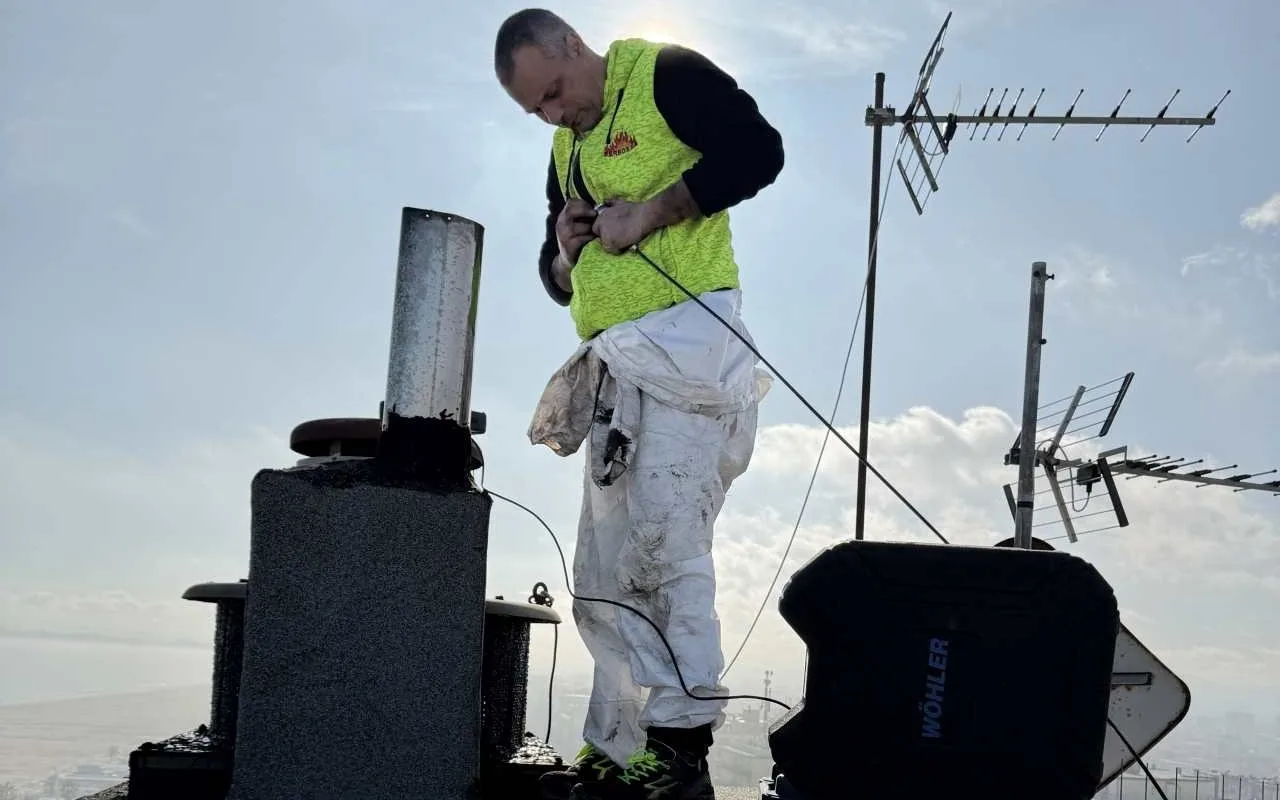 L'operatore Christian di Ferbos 2.0 impegnato in un intervento tecnico di controllo e pulizia di una canna fumaria sul tetto di un edificio.